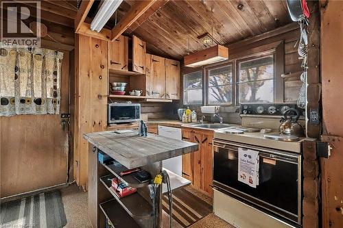 Kitchen with electric range, open shelves, white dishwasher, brown cabinetry, and stainless steel microwave - 6361 16Th Line, Minto, ON - Indoor