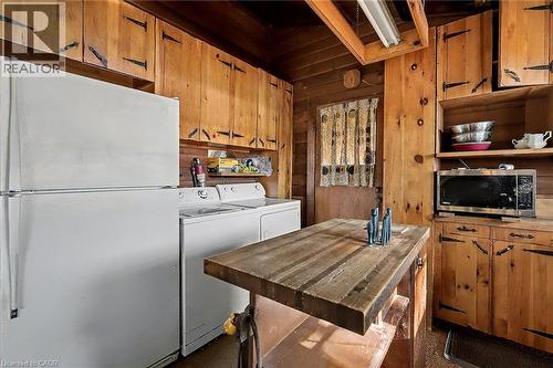 Kitchen featuring freestanding refrigerator, wood walls, open shelves, stainless steel microwave, and brown cabinetry - 6361 16Th Line, Minto, ON - Indoor