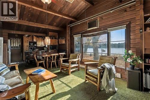 Living area featuring wooden walls, carpet flooring, a wood ceiling with exposed beams, high vaulted ceiling, and a ceiling fan - 6361 16Th Line, Minto, ON - Indoor