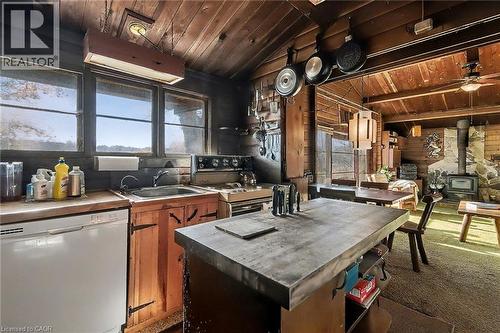 Kitchen featuring wooden ceiling, white appliances, wood walls, a wood stove, and carpet - 6361 16Th Line, Minto, ON - Indoor