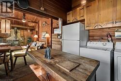 Dining space featuring a wood stove, ceiling fan, wooden walls, wooden ceiling, and dark carpet - 
