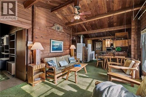Living room with wood walls, carpet flooring, a ceiling fan, wood ceiling, and a wood stove - 6361 16Th Line, Minto, ON - Indoor