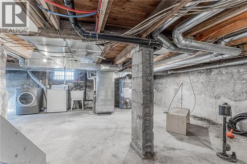 Unfinished basement featuring water heater, independent washer and dryer, and drainage system - 20 East 27Th Street, Hamilton, ON - Indoor Photo Showing Basement