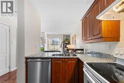 Kitchen featuring range with electric stovetop, stainless steel dishwasher, dark wood finished floors, and wood finish cabinets - 