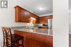 Kitchen featuring a peninsula, light stone countertops, a breakfast bar area, stainless steel appliances, and light wood-style floors - 