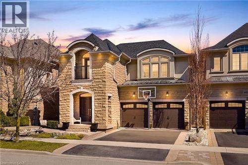 French country home with stone siding, driveway, an attached garage, and stucco siding - 4670 Bracknell Road, Burlington, ON - Outdoor With Facade