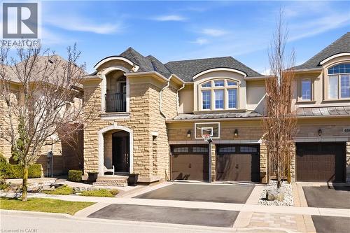 French provincial home with stone siding, a garage, driveway, stucco siding, and a balcony - 4670 Bracknell Road, Burlington, ON - Outdoor With Facade