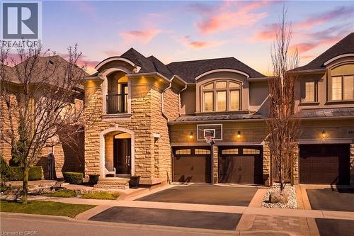 French country inspired facade with stone siding, asphalt driveway, an attached garage, and a balcony - 4670 Bracknell Road, Burlington, ON - Outdoor With Facade