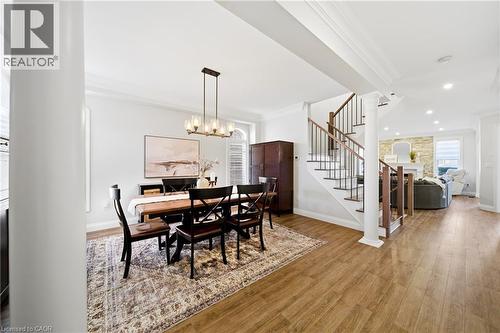 Dining space with crown molding, a stone fireplace, wood finished floors, decorative columns, and hanging lights - 4670 Bracknell Road, Burlington, ON - Indoor Photo Showing Dining Room