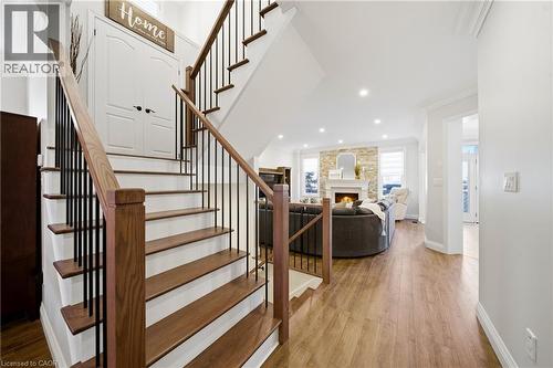 Stairs with wood finished floors, a large fireplace, ornamental molding, and recessed lighting - 4670 Bracknell Road, Burlington, ON - Indoor Photo Showing Other Room