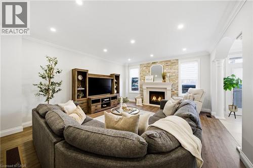 Living area with crown molding, a large fireplace, arched walkways, wood finished floors, and recessed lighting - 4670 Bracknell Road, Burlington, ON - Indoor Photo Showing Living Room With Fireplace
