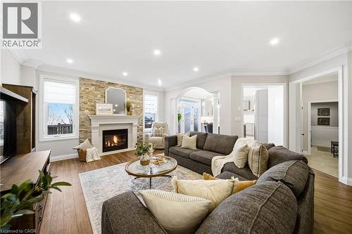 Living room featuring crown molding, a fireplace, hardwood / wood-style floors, arched walkways, and recessed lighting - 4670 Bracknell Road, Burlington, ON - Indoor Photo Showing Living Room With Fireplace