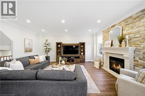 Living area featuring ornamental molding, wood finished floors, and a glass covered fireplace - 4670 Bracknell Road, Burlington, ON - Indoor Photo Showing Living Room With Fireplace
