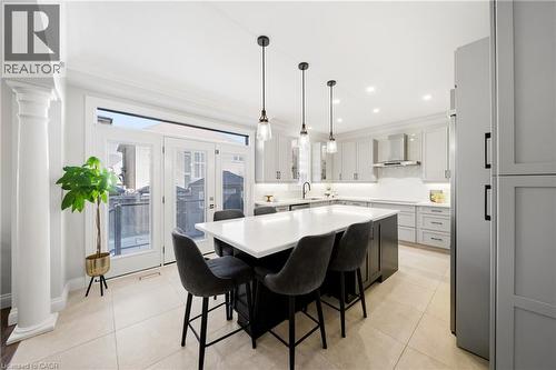 Kitchen featuring ornate columns, a kitchen island, a kitchen breakfast bar, light tile patterned flooring, and two tone cabinets - 4670 Bracknell Road, Burlington, ON - Indoor