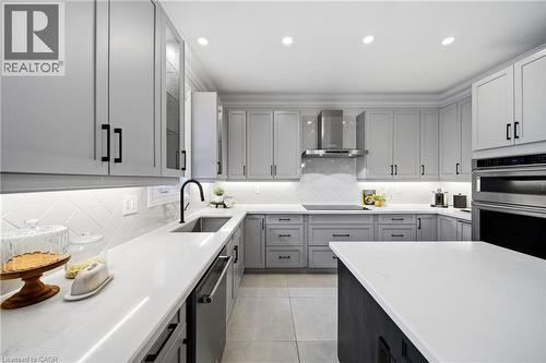 Kitchen with stainless steel appliances, recessed lighting, backsplash, light stone counters, and gray cabinetry - 4670 Bracknell Road, Burlington, ON - Indoor Photo Showing Kitchen