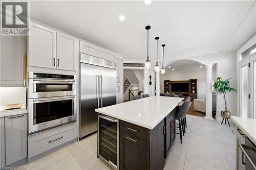 Two tone kitchen featuring stainless steel appliances, beverage cooler, open floor plan, a kitchen breakfast bar, and a center island - 4670 Bracknell Road, Burlington, ON - Indoor Photo Showing Kitchen With Upgraded Kitchen