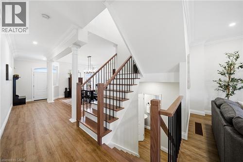 Stairs featuring crown molding, wood finished floors, suspended lighting, and decorative columns - 4670 Bracknell Road, Burlington, ON - Indoor Photo Showing Other Room