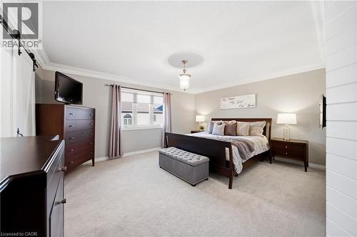 Bedroom featuring ornamental molding, light colored carpet, and a barn door - 4670 Bracknell Road, Burlington, ON - Indoor Photo Showing Bedroom