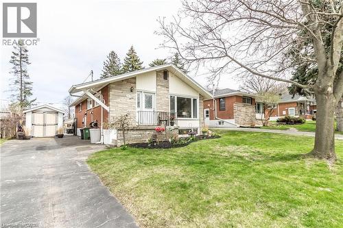 View of front of home with a shed, stone siding, asphalt driveway, and a front yard - 11 Carwyn Crescent, Hamilton, ON - Outdoor With Facade