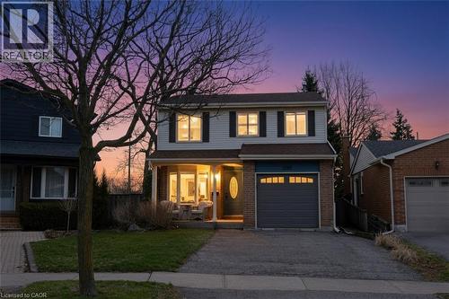 Traditional-style house with covered porch, asphalt driveway, a lawn, brick, siding, and a garage - 3200 Greenbough Crescent, Burlington, ON - Outdoor With Facade