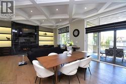 Dining room featuring coffered ceiling, light wood-style floors, a large fireplace, and recessed lighting - 