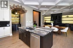 Two tone kitchen featuring stainless steel dishwasher, coffered ceiling, an island with sink, beverage cooler, and recessed lighting - 