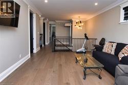 Living room with wood finished floors, suspended lighting, and crown molding - 
