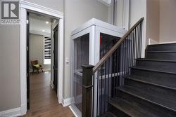 Stairs with wood finished floors, ornamental molding, and elevator - 