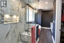 Bathroom with vanity, a marble finish shower, and hanging lights - 