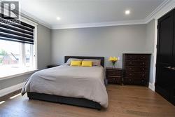 Bedroom with dark wood-style flooring, ornamental molding, and recessed lighting - 