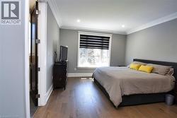 Bedroom featuring dark wood-style floors and crown molding - 