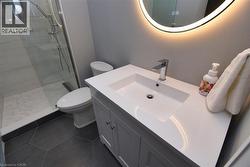 Full bath with vanity, a tile shower, and dark tile patterned floors - 