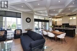 Living area with coffered ceiling, light wood-style floors, recessed lighting, and crown molding - 