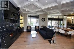 Living area with coffered ceiling, light wood-type flooring, recessed lighting, ornamental molding, and a high end fireplace - 