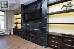 Detailed view of coffered ceiling, wood finished floors, ornamental molding, a high end fireplace, and recessed lighting - 