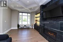 Sitting room with coffered ceiling, light wood-type flooring, a tile fireplace, recessed lighting, and ornamental molding - 