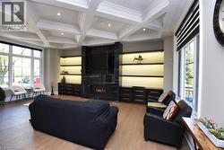 Living area featuring coffered ceiling, wood finished floors, a large fireplace, recessed lighting, and ornamental molding - 