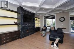 Living area featuring coffered ceiling, a fireplace, light wood-style floors, crown molding, and recessed lighting - 