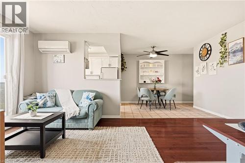 Living area with medium vinyl wood-type flooring, a wall mounted air conditioner, and ceiling fan - 2373 E King Street E Unit# 45, Hamilton, ON - Indoor Photo Showing Living Room