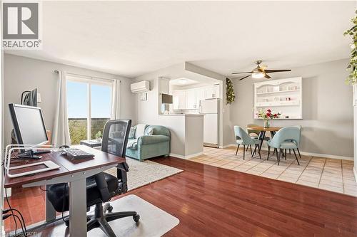 Open concept office area/living room with medium vinyl wood-style flooring, ceiling fan, and a wall mounted air conditioner - 2373 E King Street E Unit# 45, Hamilton, ON - Indoor