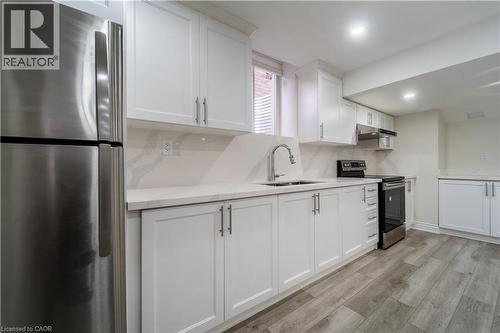 Kitchen with stainless steel appliances, white cabinets, light wood-type flooring, backsplash, and recessed lighting - 150 Goodwin Crescent Unit# Bsmt, Milton, ON - Indoor Photo Showing Kitchen