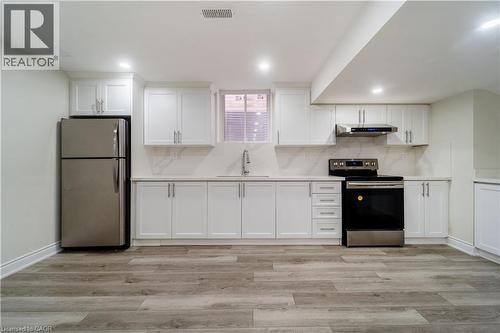 Kitchen with white cabinetry, stainless steel appliances, backsplash, light wood-type flooring, and recessed lighting - 150 Goodwin Crescent Unit# Bsmt, Milton, ON - Indoor Photo Showing Kitchen