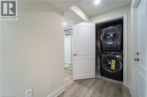 Laundry area featuring light wood-type flooring and stacked washer and dryer - 150 Goodwin Crescent Unit# Bsmt, Milton, ON - Indoor Photo Showing Laundry Room