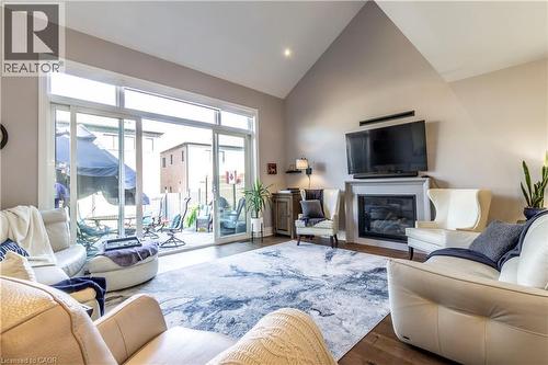 Living area featuring a glass covered fireplace, vaulted ceiling, and wood finished floors - 72 Pond View Gate, Waterdown, ON - Indoor Photo Showing Living Room With Fireplace