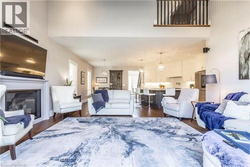 Living area featuring a glass covered fireplace, dark wood finished floors, and a high ceiling - 72 Pond View Gate, Waterdown, ON - Indoor Photo Showing Living Room With Fireplace