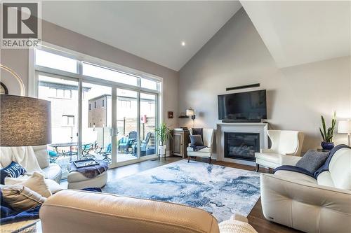 Living room with lofted ceiling, a glass covered fireplace, wood finished floors, and recessed lighting - 72 Pond View Gate, Waterdown, ON - Indoor Photo Showing Living Room With Fireplace