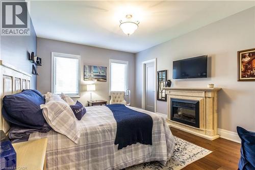 Bedroom featuring a glass covered fireplace and dark wood finished floors - 72 Pond View Gate, Waterdown, ON - Indoor With Fireplace