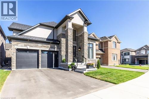 View of front of house featuring stone siding, a front lawn, and driveway - 72 Pond View Gate, Waterdown, ON - Outdoor With Facade