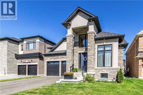 View of front of home with stone siding, a front lawn, and driveway - 72 Pond View Gate, Waterdown, ON - Outdoor With Facade