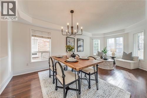 Dining area with dark wood-type flooring, a chandelier, and a raised ceiling - 5811 Page Crescent, Burlington, ON - Indoor Photo Showing Dining Room
